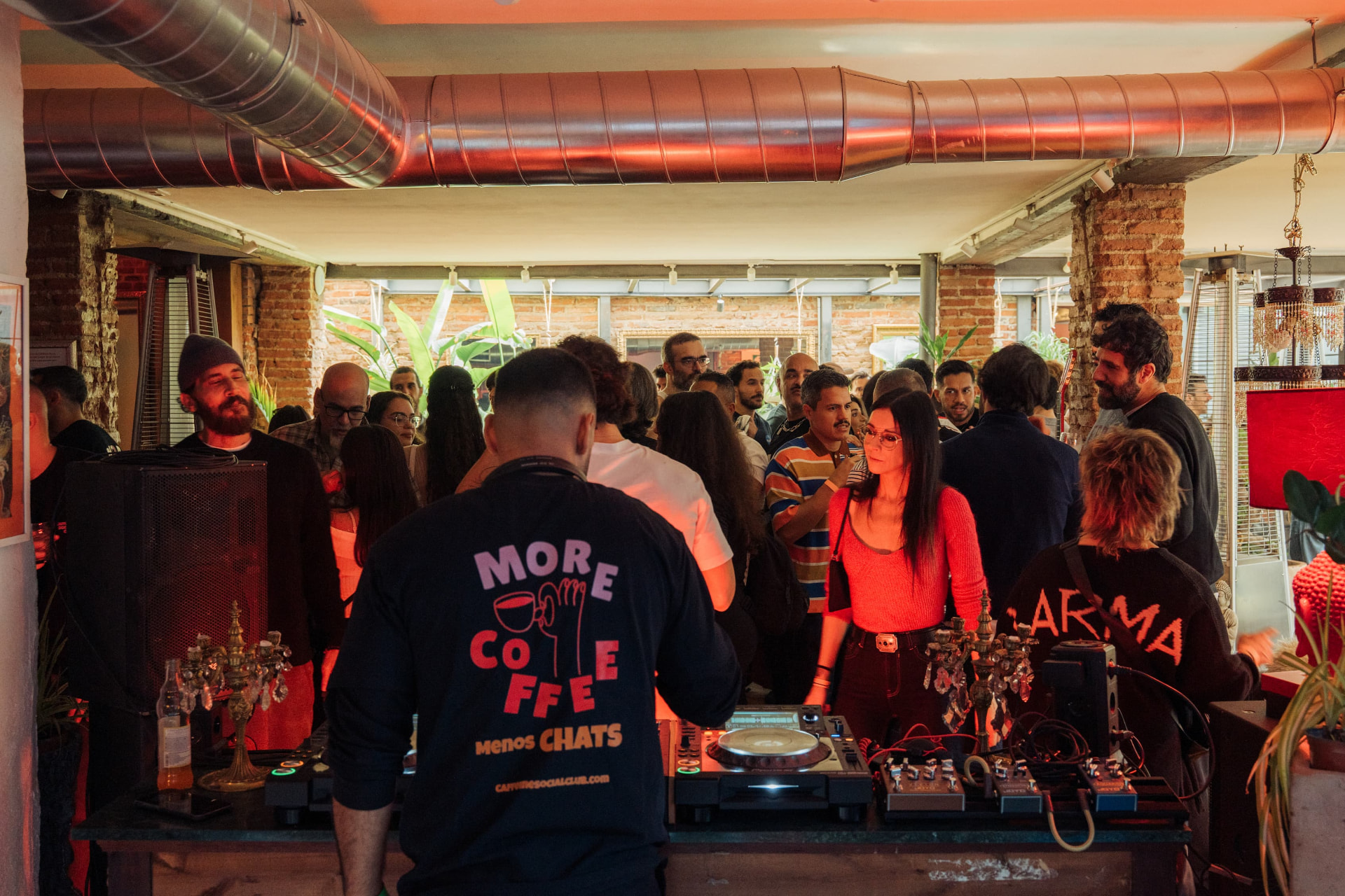 Gente de fiesta en un tardeo en Madrid junto al DJ con luces rojas
